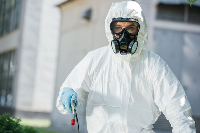 Image of operative spraying and wearing protective equipment with respirator